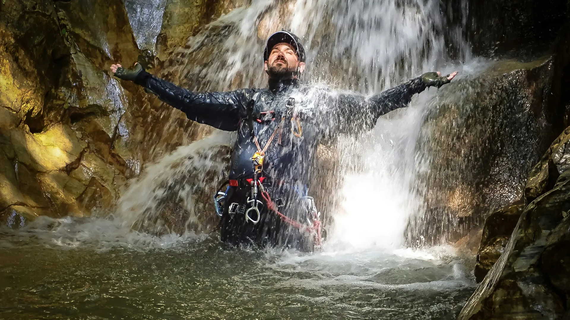 Un canyoniste en combinaison glissant le long d’une cascade dans une piscine naturelle turquoise près d’Interlaken
