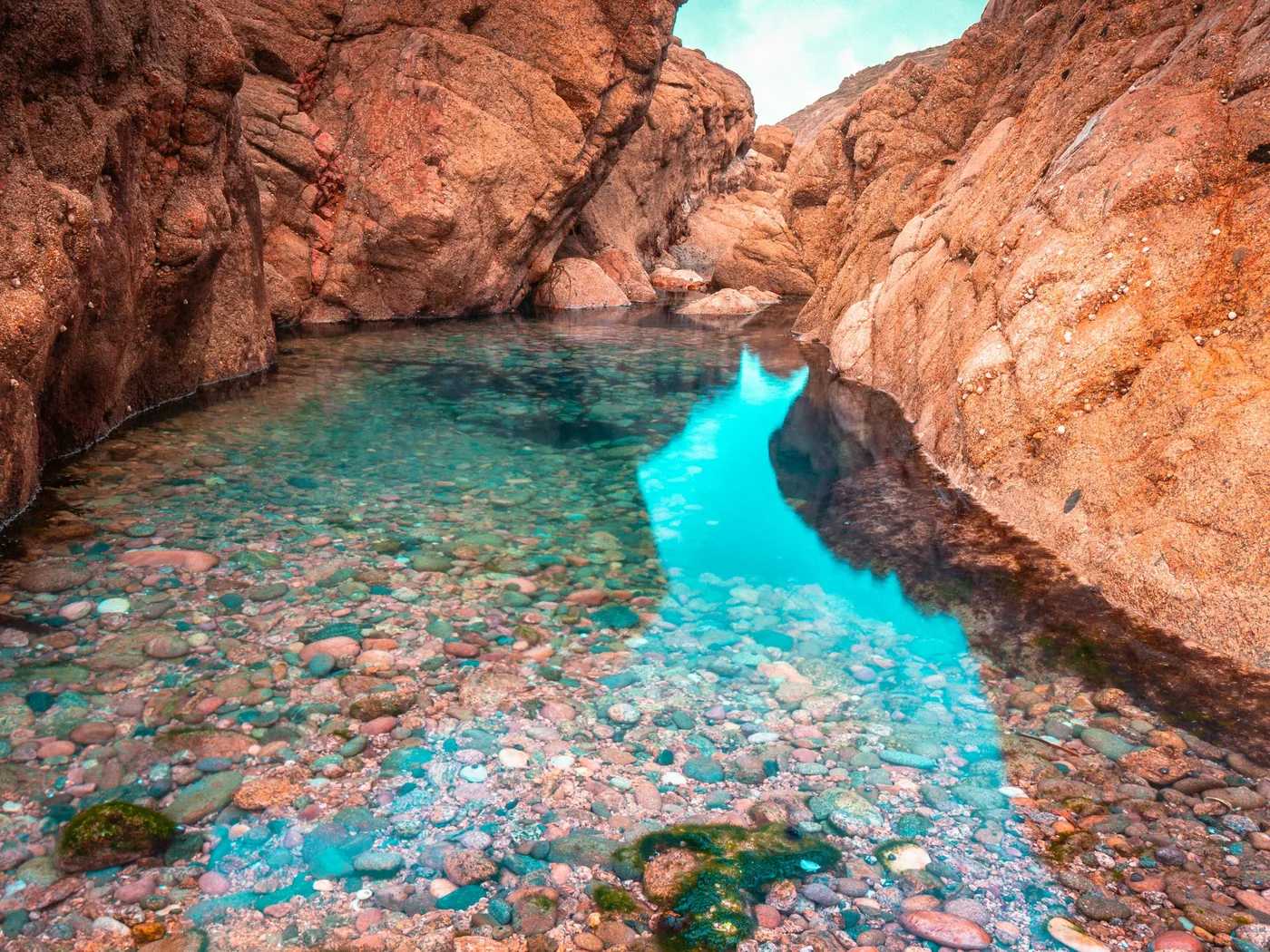 Bassin turquoise limpide en contrebas de falaises rocheuses