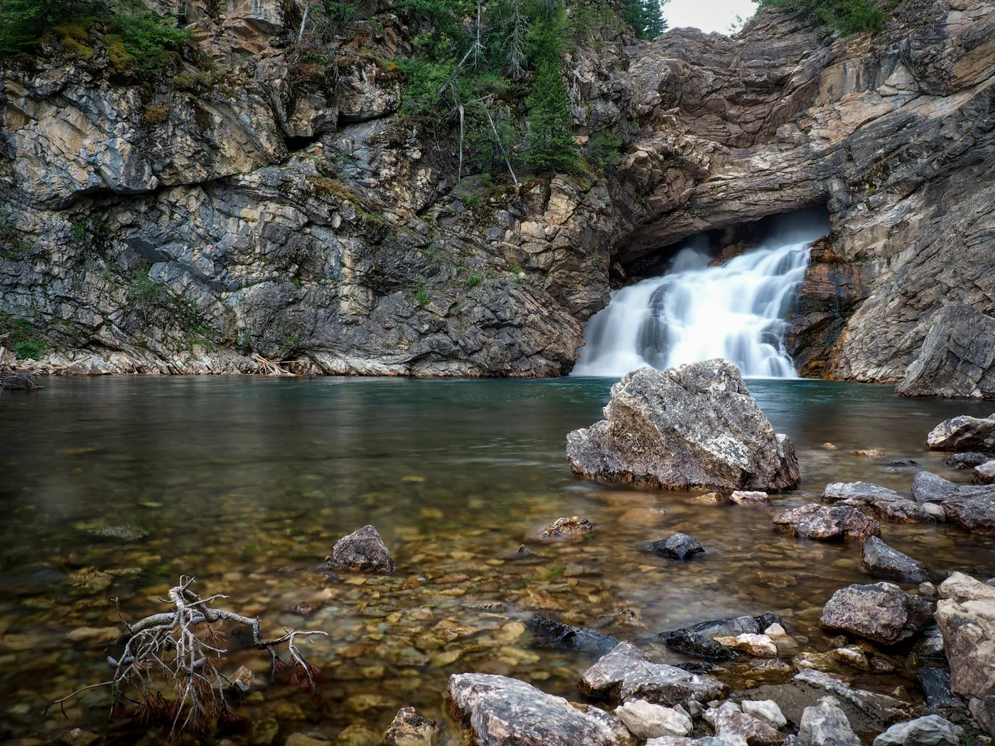 Une cascade se jetant dans un bassin profond au cœur d'un canyon alpin